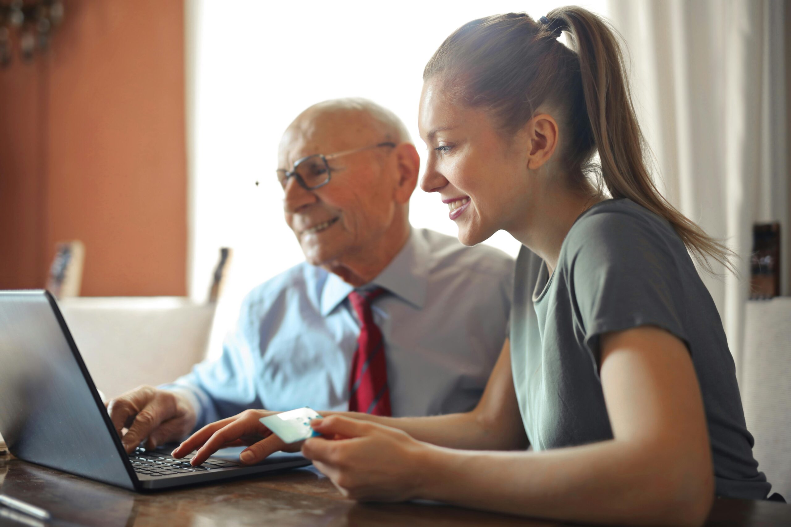 A woman and an older businessman sitting next to each other looking at a laptop screen