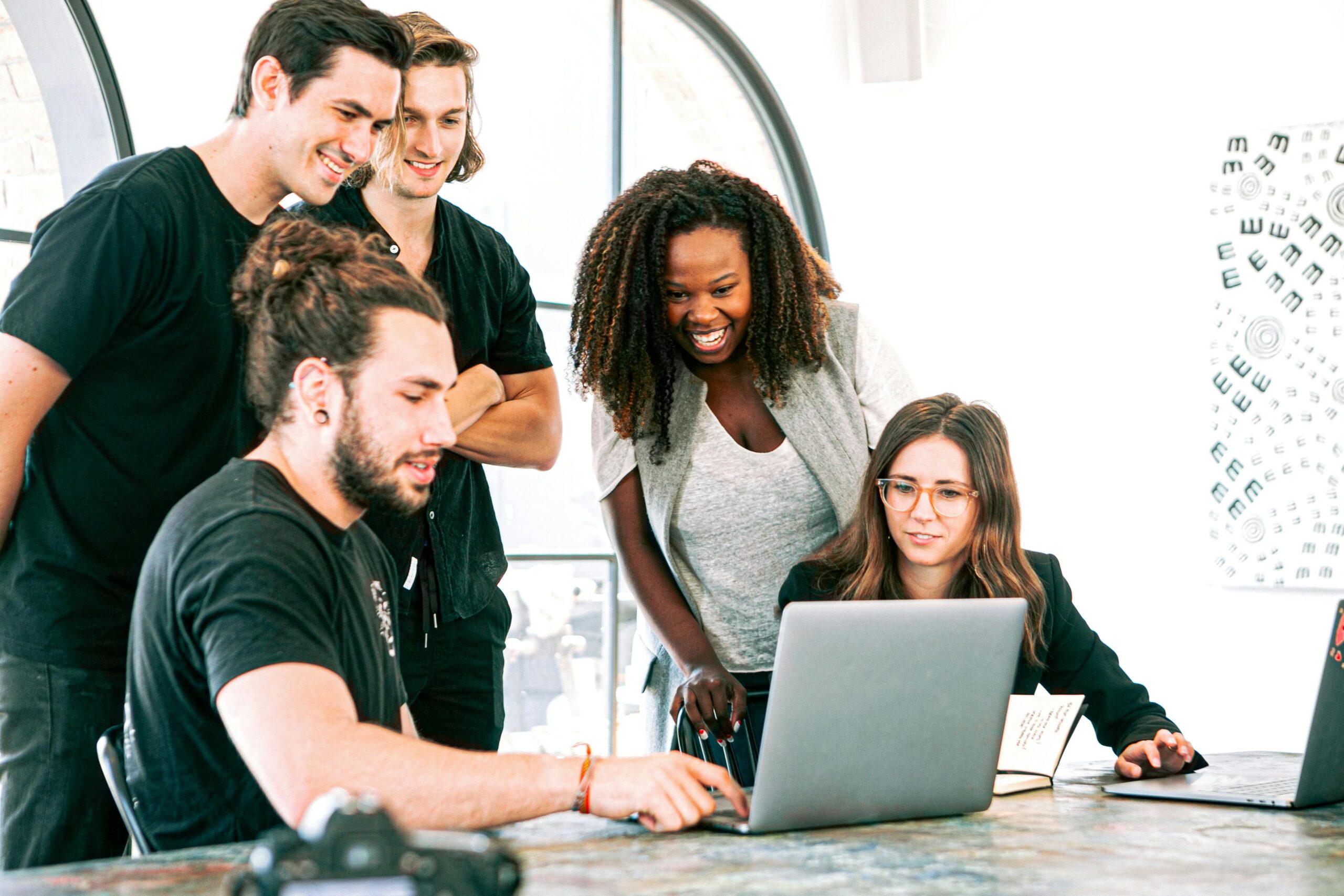 A group of people looking at a computer scene happily.